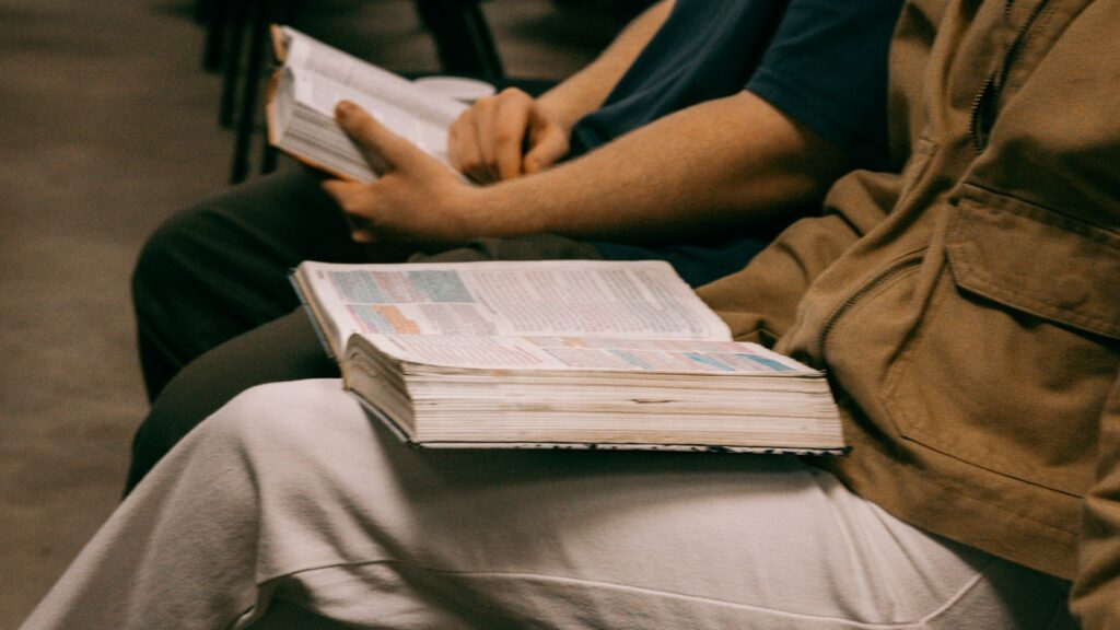 Pessoas estudando livros abertos em reunião, imagem ilustrativa sobre liderança cristã e ensino bíblico