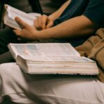 Pessoas estudando livros abertos em reunião, imagem ilustrativa sobre liderança cristã e ensino bíblico