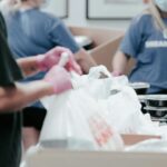 Voluntários organizam alimentos em equipe, imagem ilustrativa da cooperação ensinada na Lição 5 sobre Timóteo e Epafrodito