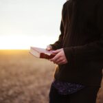 Pessoa com Bíblia ao pôr do sol, imagem sobre serviço e esperança — lição 10