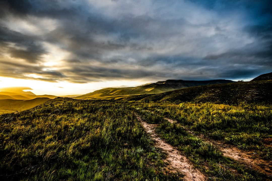Caminho entre colinas iluminadas pelo pôr do sol, simbolizando perseverança e vida digna do Evangelho em Filipenses 1.27