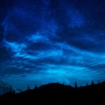 Céu noturno estrelado sobre paisagem de montanhas, simbolizando os astros que resplandecem em Filipenses 2.15
